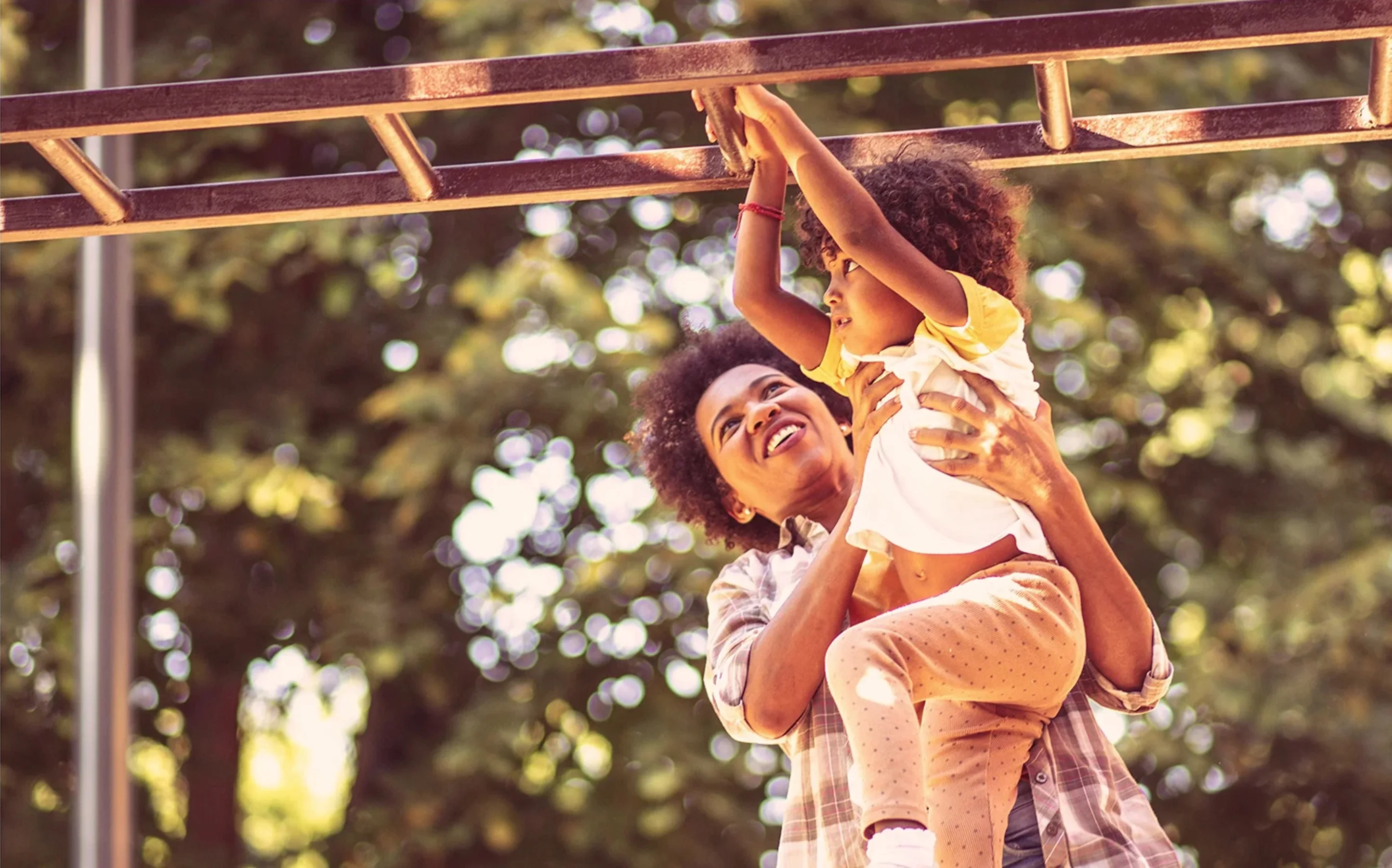 Mother helping her daughter on a playground