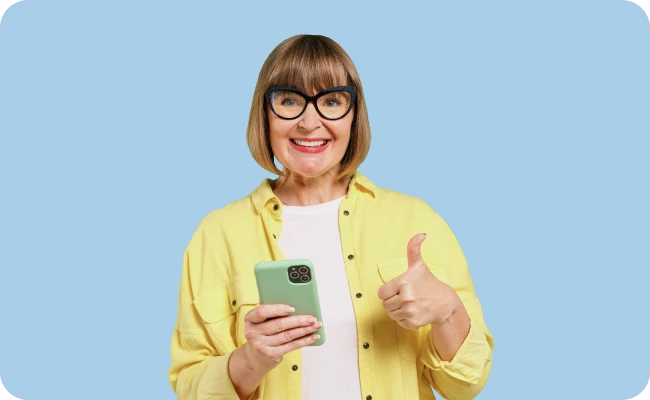 women smiling holding a phone and giving a thumbs up